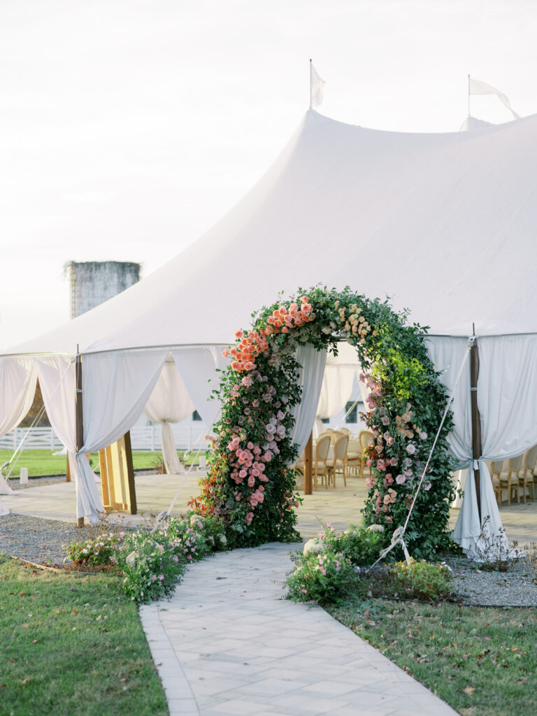 Sailcloth tent with draped white curtains and a lush floral arch at Northfield Estate in Virginia.