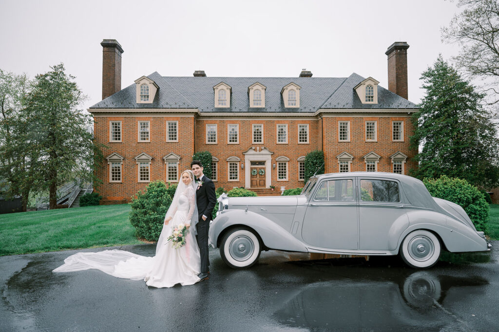 Bride and groom standing beside a vintage Rolls Royce in front of The Estate at River Run, a luxury Virginia wedding venue.
