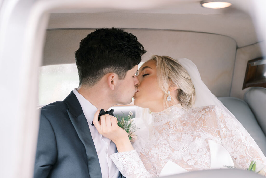 Bride and groom share a kiss inside a classic vintage car at The Estate at River Run in Richmond, Virginia.