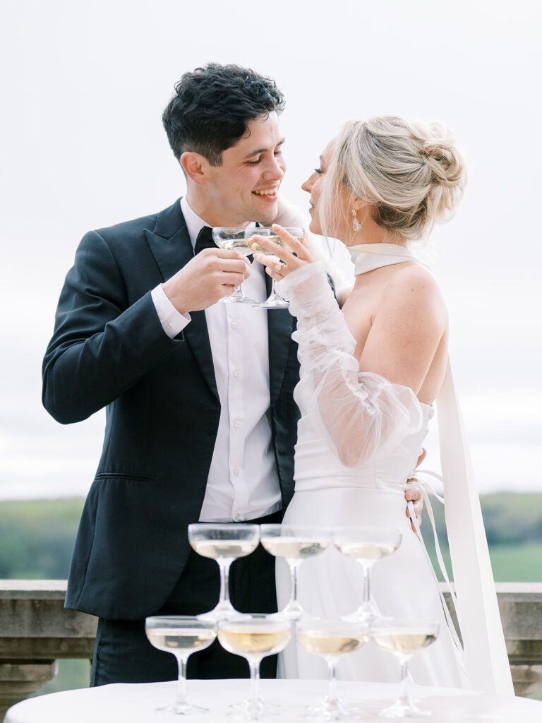 Bride and groom toast with champagne beside a coupe tower on the terrace at The Estate at River Run in Richmond, Virginia.